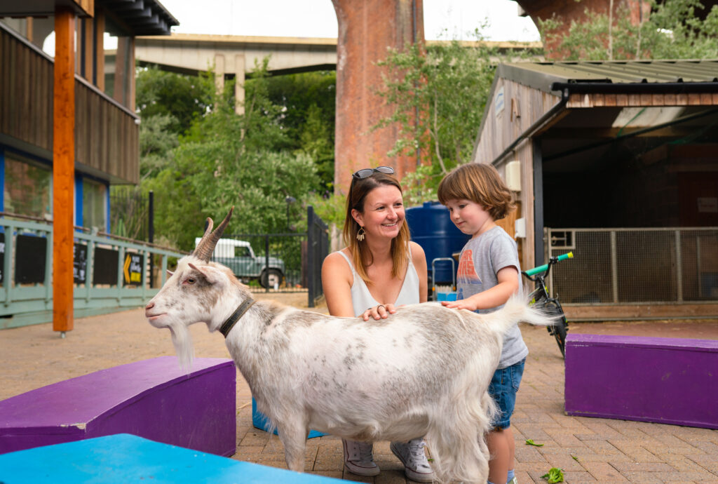 Mother and child in urban farm Ouseburn Farm petting a small goat.